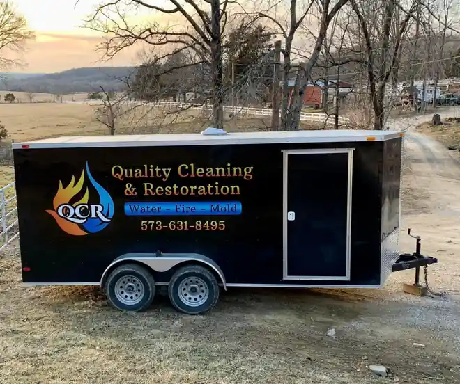 The black QCR work trailer parked in an open field at golden hour