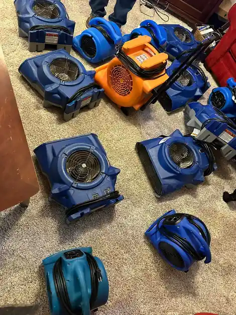 A ring of blue air movers drying a carpeted room