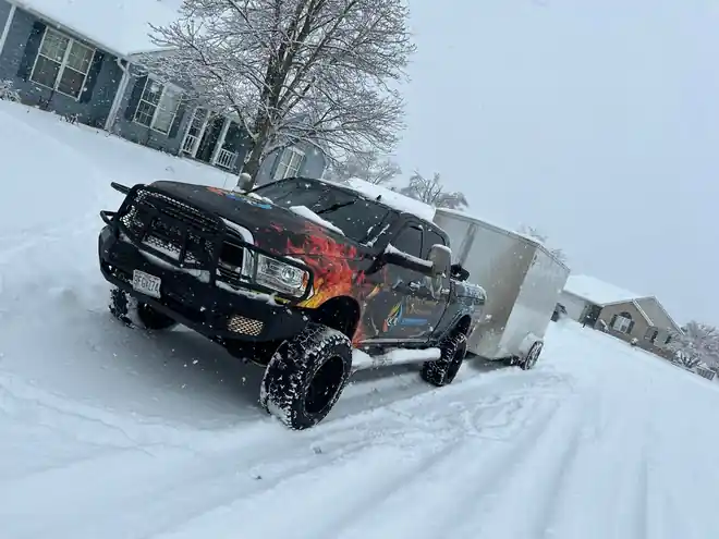The wrapped QCR truck towing a trailer through snow