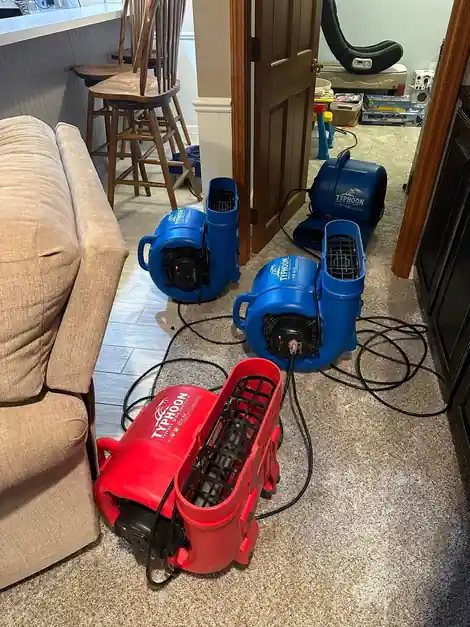 Red and blue air movers drying a living room floor