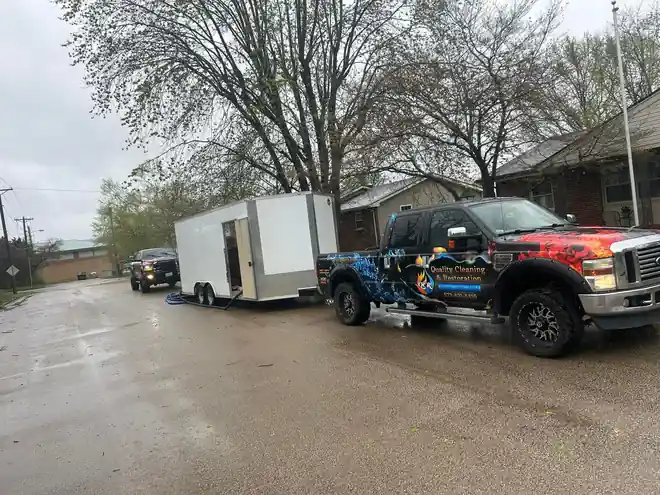 The wrapped QCR truck and a white trailer on a wet road