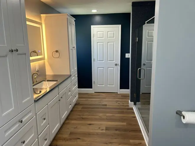 Finished bathroom with a navy wall, vanity and backlit mirror