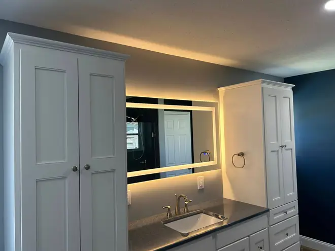 Double-door cabinet and backlit mirror in a remodeled bathroom
